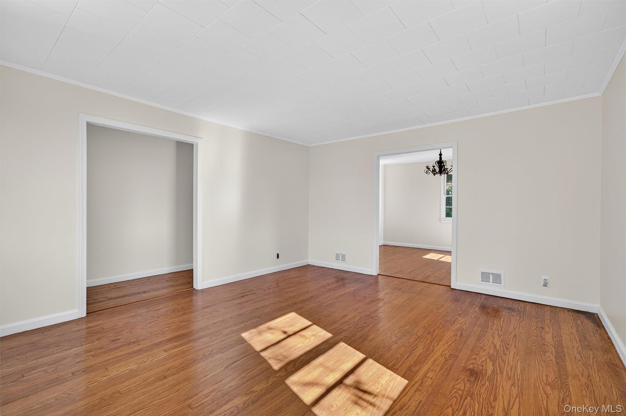 12 Mid Oaks Road Monroe, NY 10950 - Photo 16 of 44 Empty room with ornamental molding, a chandelier, and wood finished floors