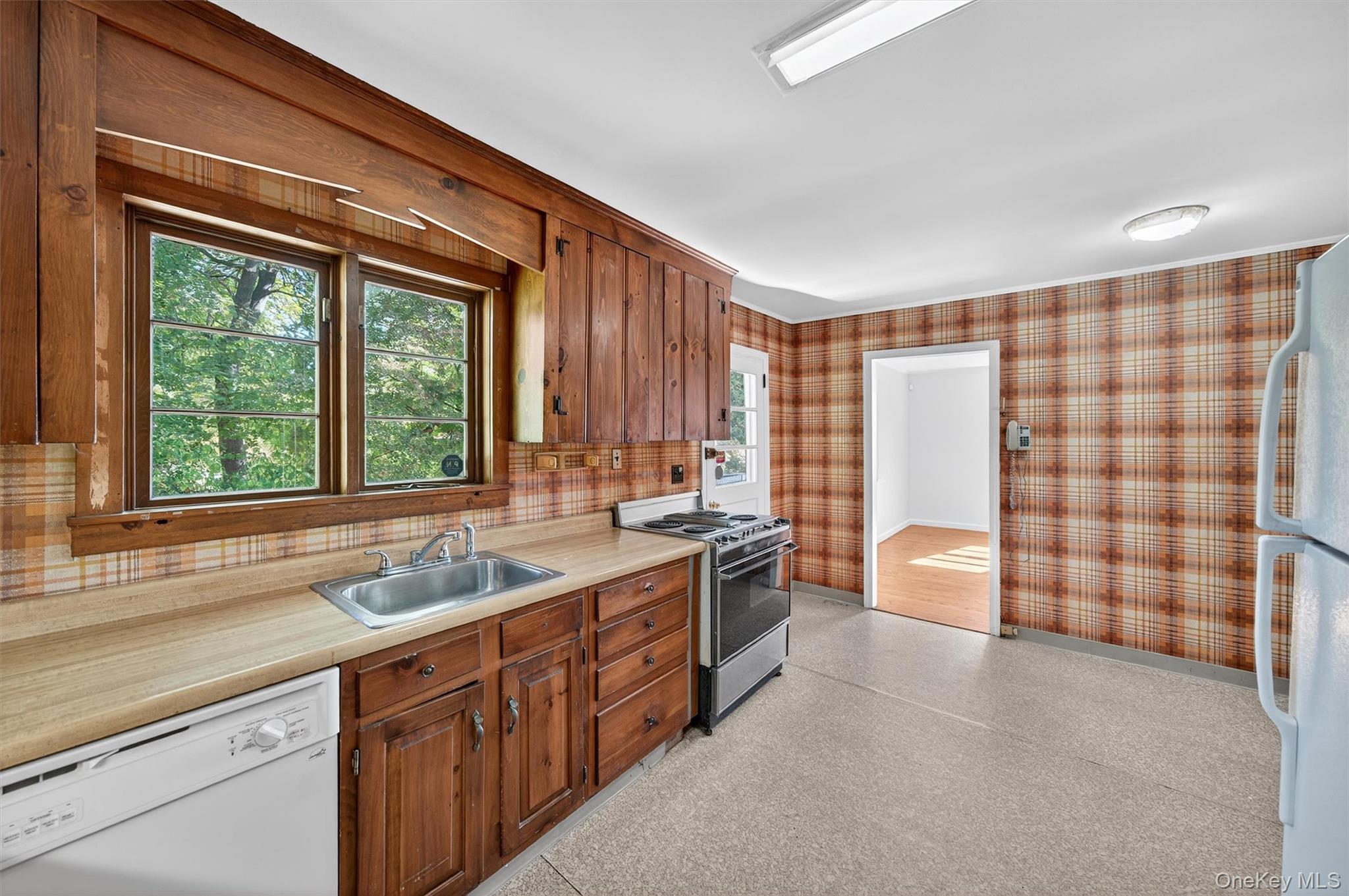 12 Mid Oaks Road Monroe, NY 10950 - Photo 23 of 44 Kitchen with white appliances, light countertops, wallpapered walls, and brown cabinetry