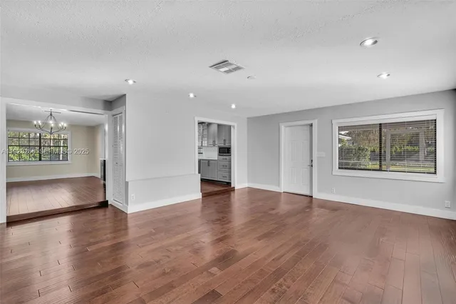 an empty room with wooden floor fireplace and windows