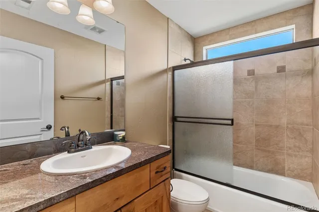 a bathroom with a granite countertop sink toilet and shower