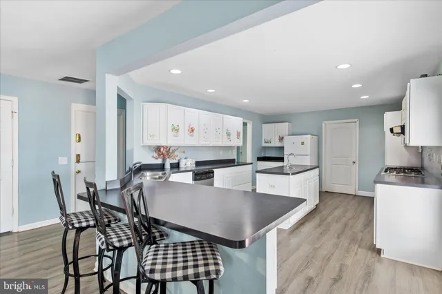 a kitchen with stainless steel appliances kitchen island granite countertop a table chairs and a refrigerator