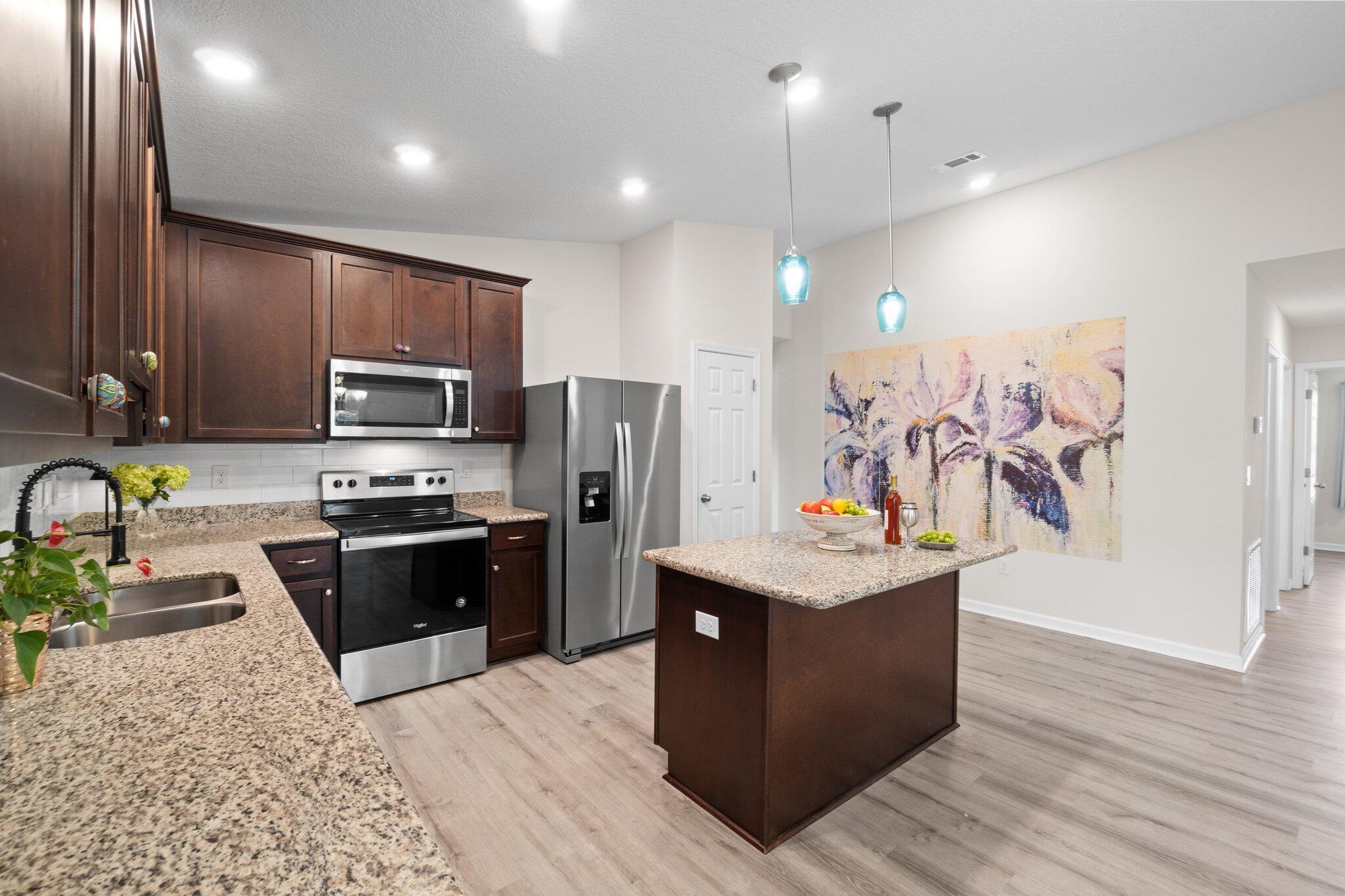 378 Marquis Way Freeport, FL 32439 - Photo 8 of 37 a kitchen with stainless steel appliances kitchen island granite countertop a stove refrigerator and microwave