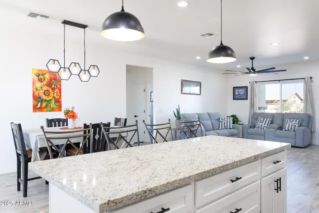 a kitchen with granite countertop a table a chandelier and living room view