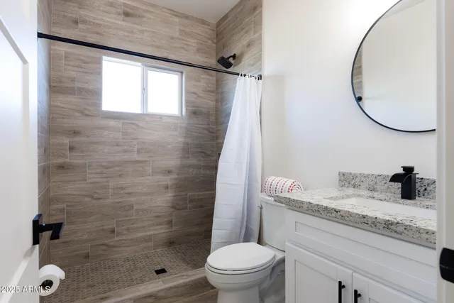 a bathroom with a granite countertop sink a toilet and shower