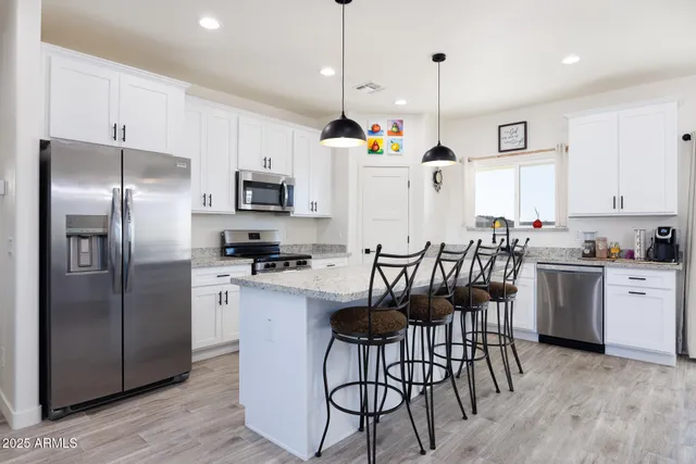 a kitchen with granite countertop a refrigerator stove a sink a dining table and chairs