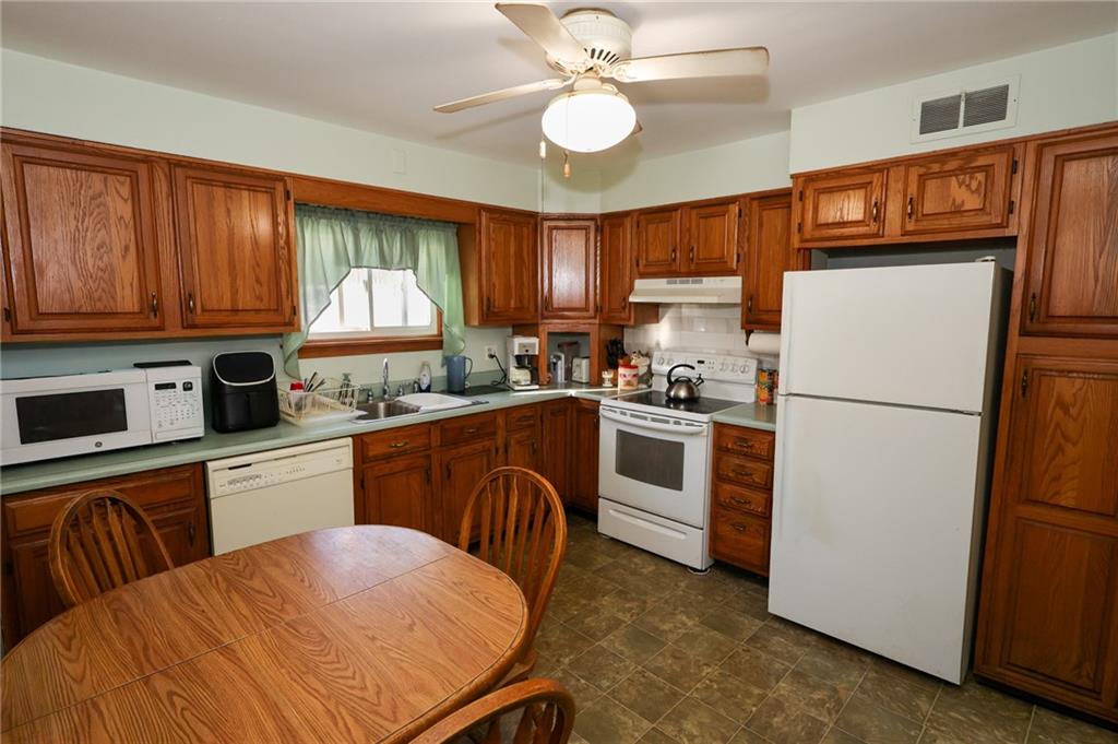521 Mercer-New Wilmington Road Mercer, PA 16137 - Photo 4 of 35 a kitchen with a refrigerator a stove top oven a sink dishwasher and white cabinets with wooden floor