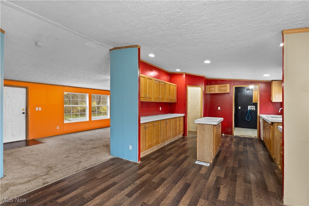 12859 Narrows Road Cambridge, OH 43725 - Photo 12 of 29 Kitchen featuring dark hardwood / wood-style flooring, a textured ceiling, vaulted ceiling, sink, and a kitchen island