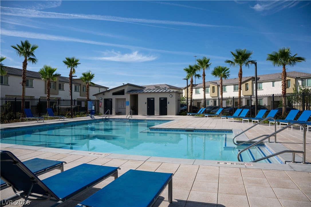12267 Desert Light Road, Unit 4 Las Vegas, NV 89183 - Photo 17 of 18 3 refreshing community pools with sun loungers await, bordered by lush palm trees and modern residences.