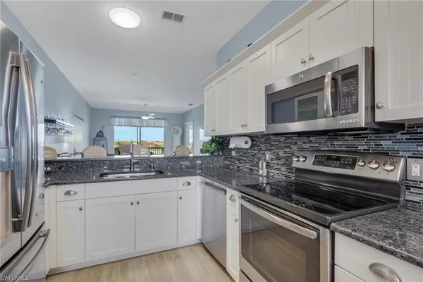 a kitchen with stainless steel appliances granite countertop a sink stove and cabinets