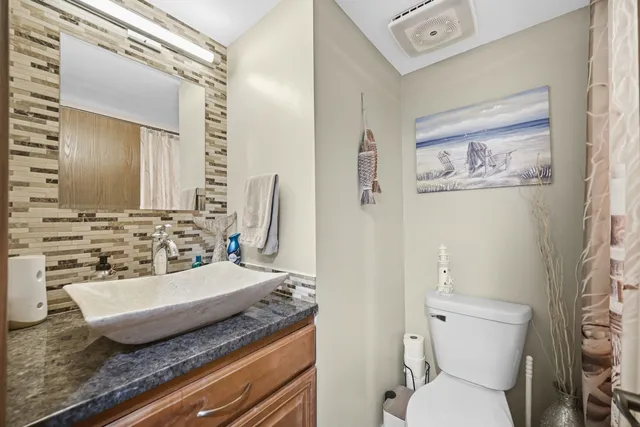 a bathroom with a granite countertop sink mirror vanity and toilet