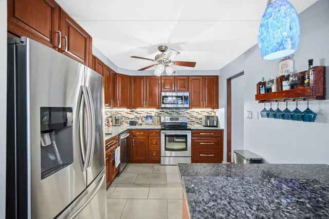 a kitchen with stainless steel appliances granite countertop a refrigerator a stove and a sink