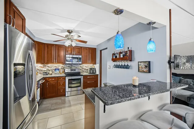 a kitchen with stainless steel appliances granite countertop a refrigerator a stove and a sink with cabinets