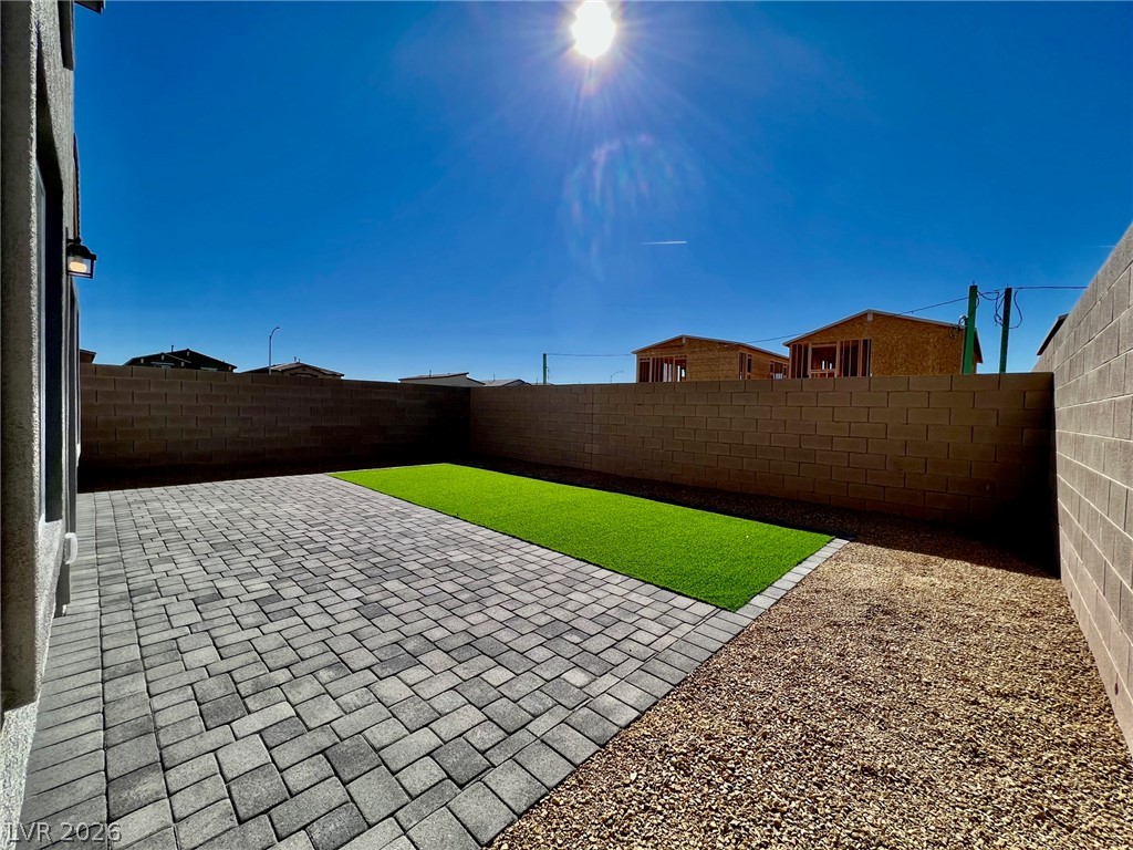7845 Morganite Avenue Las Vegas, NV 89113 - Photo 10 of 21 A low-maintenance yard offers both paved patio space and a vibrant green turf area, all enclosed by a privacy wall.