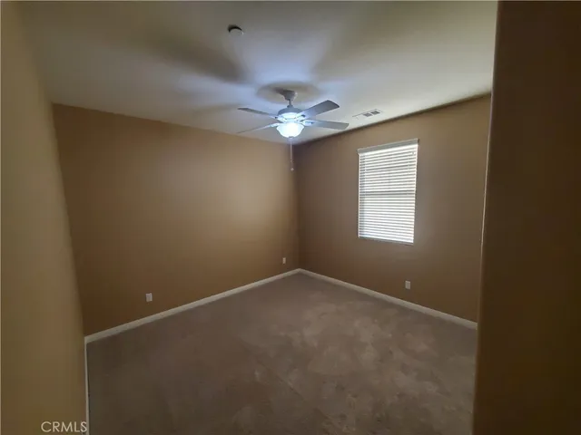 an empty room with a window and a fan