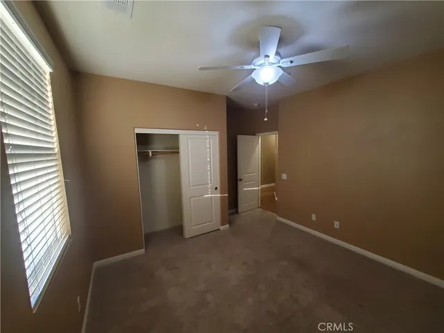 an empty room with chandelier fan and windows