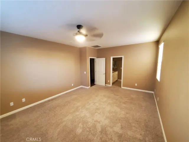 an empty room with a ceiling fan and carpet