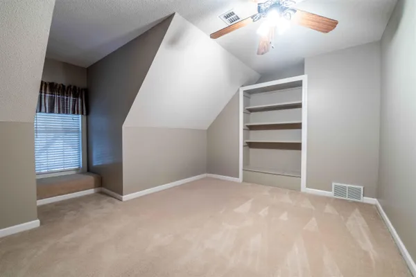 a view of an empty room with a chandelier fan