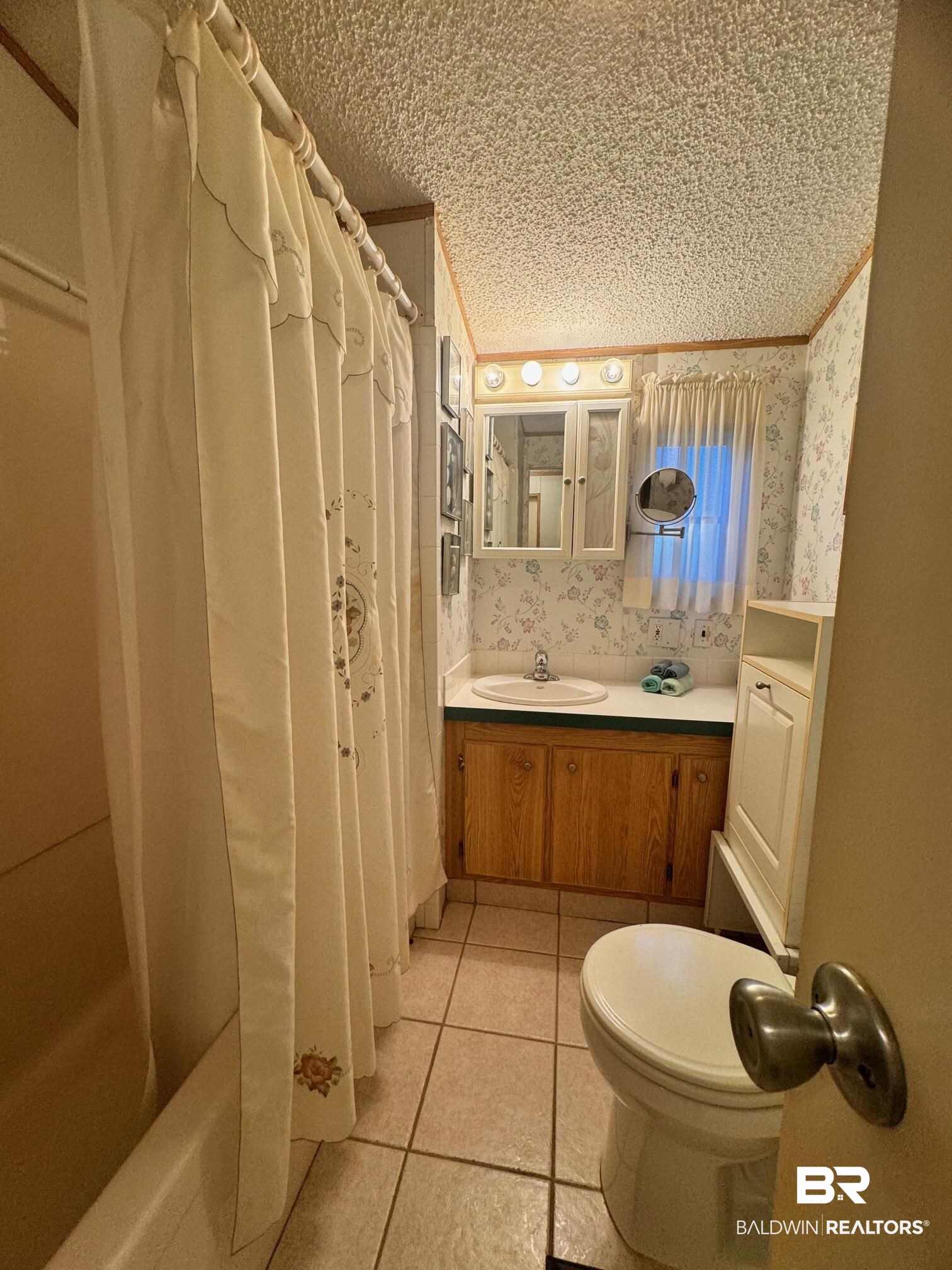 112 Horn Drive Lillian, AL 36549 - Photo 8 of 30 Full bathroom featuring tile patterned flooring, toilet, shower / bath combination with curtain, vanity, and a textured ceiling