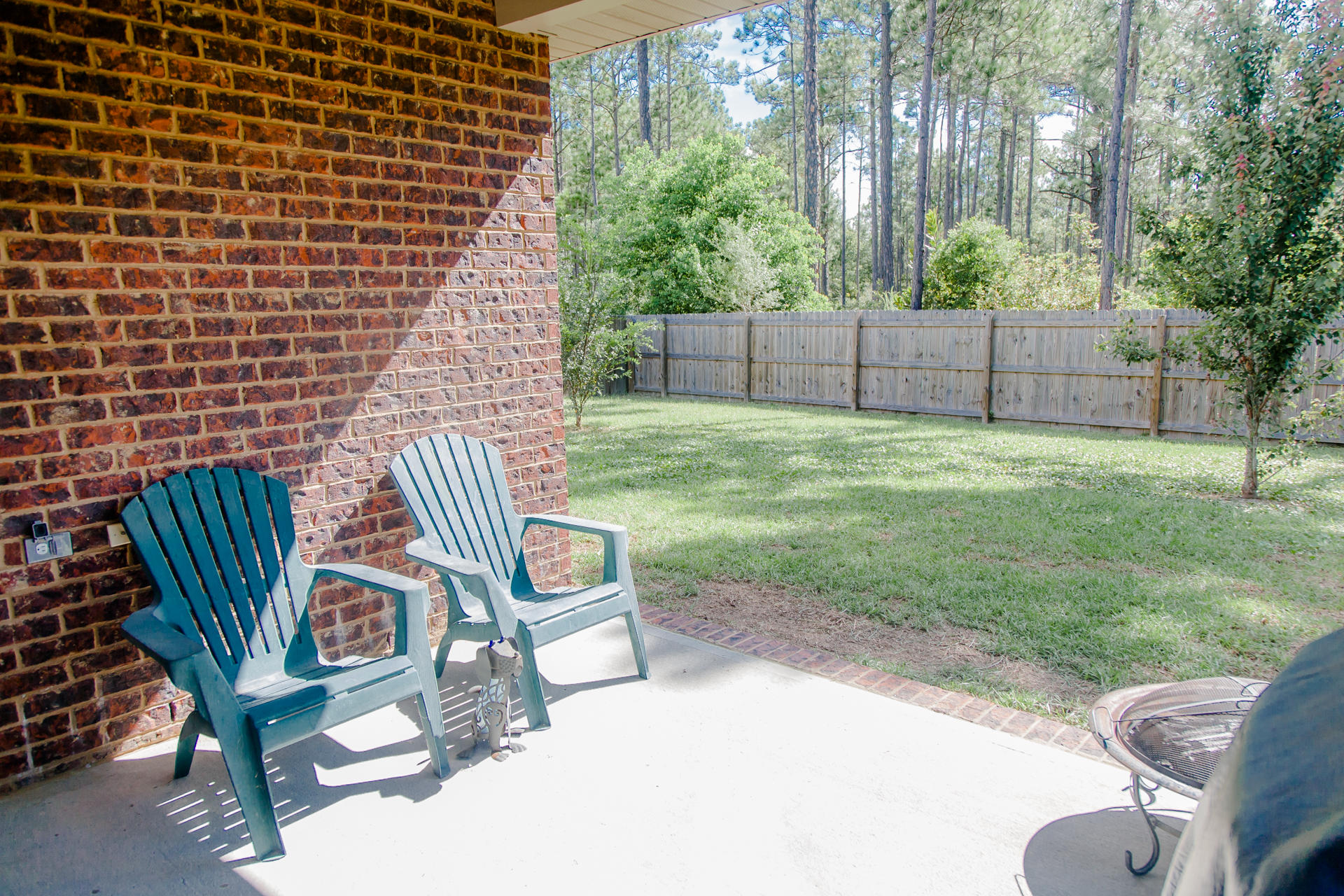 282 Whispering Lake Drive Santa Rosa Beach, FL 32459 - Photo 5 of 18 a view of a backyard with chairs potted plants and a wooden fence