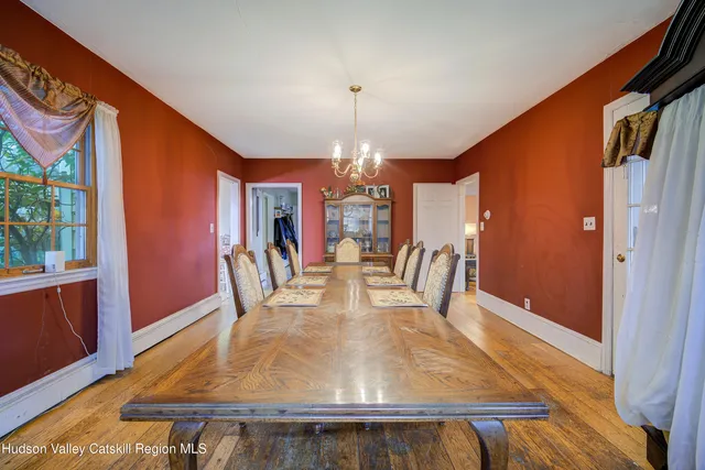 a dining room with wooden floor chandelier and glass door