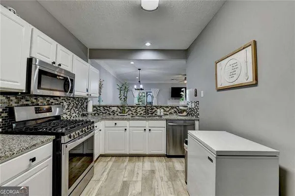 a kitchen with granite countertop a sink a stove and cabinets