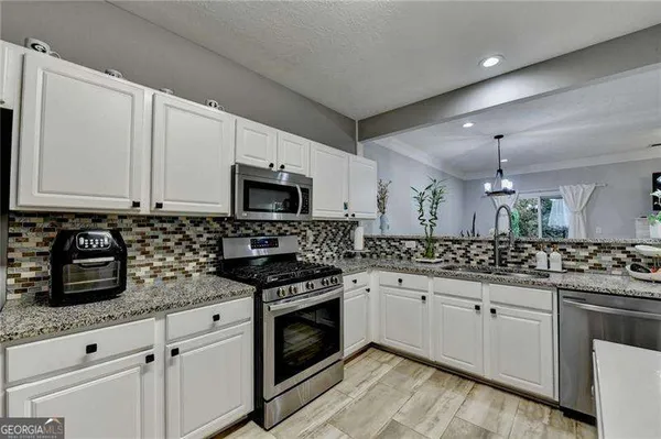 a kitchen with granite countertop white cabinets and white stove