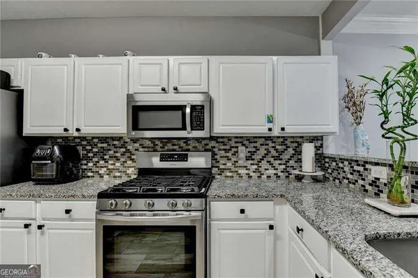 a kitchen with granite countertop a refrigerator stove and microwave
