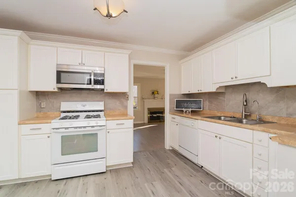 a kitchen with granite countertop white cabinets and white appliances