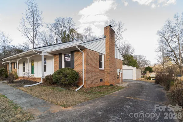 a view of a house with a yard and large trees