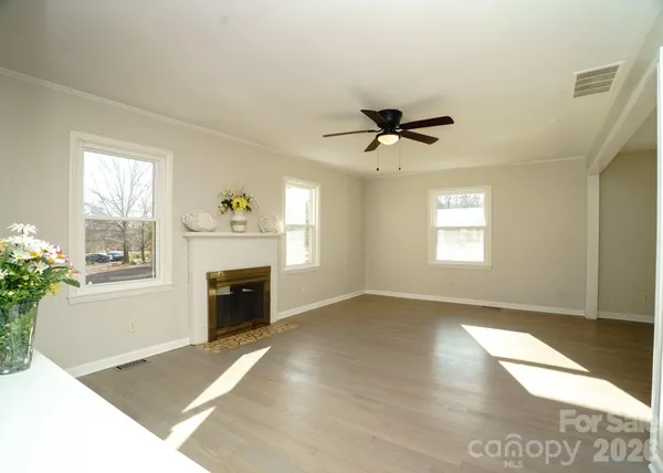 a view of a livingroom with a fireplace a ceiling fan and windows