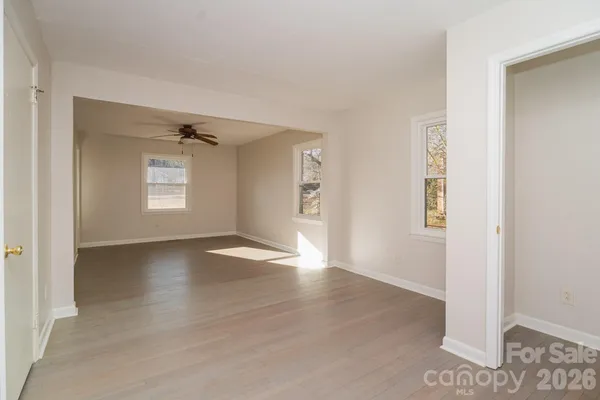 a view of an empty room with wooden floor and a window