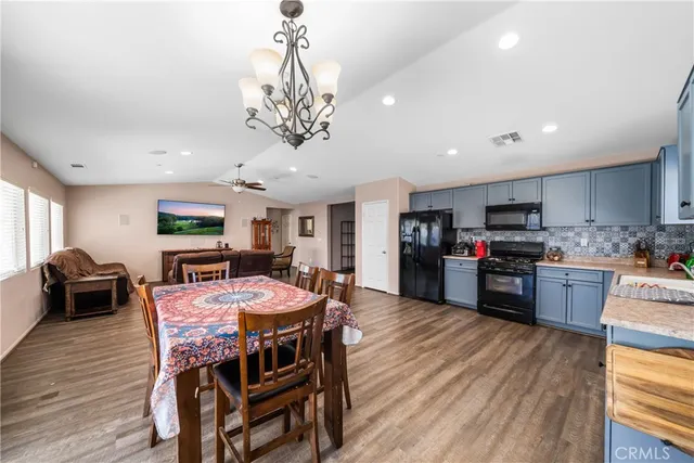 a kitchen with stainless steel appliances granite countertop a stove a refrigerator a kitchen island a dining table and chairs with wooden floor
