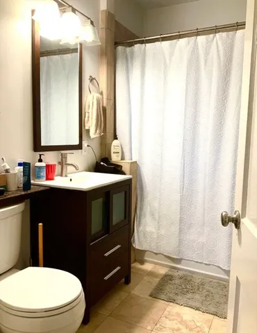 a bathroom with a sink a toilet a mirror and shower curtain