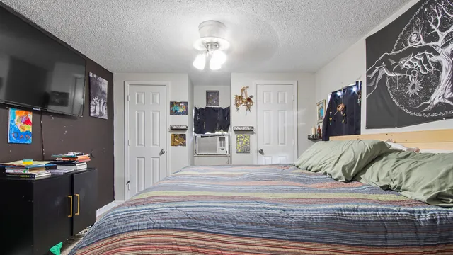 a bedroom with a bed and a flat tv screen on wall