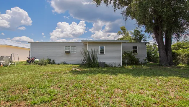 a backyard of a house with plants and large tree