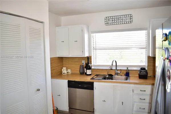 a kitchen with stainless steel appliances granite countertop white cabinets sink and a window