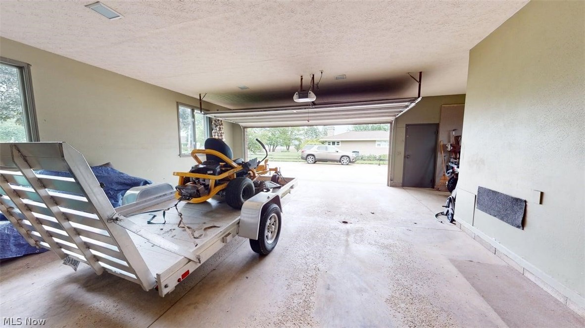 3985 Wiers Road Willard, OH 44890 - Photo 39 of 50 Spacious garage featuring a concrete floor, an overhead garage door, an automatic opener, interior lighting, and a side access door