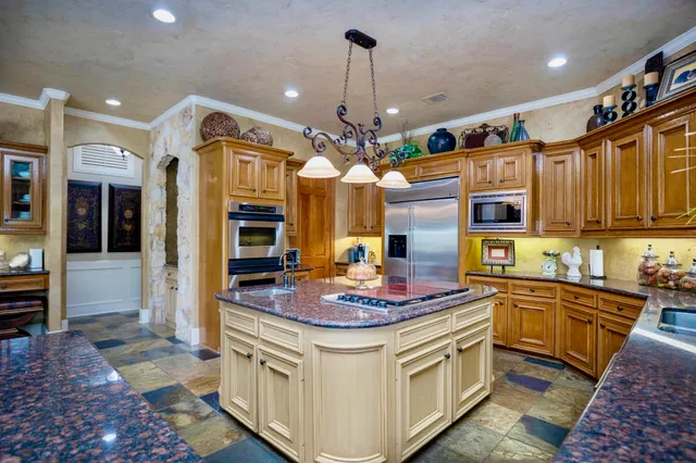 a kitchen with stainless steel appliances granite countertop a sink a stove and cabinets