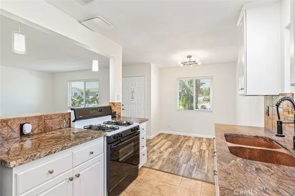 a kitchen with granite countertop a sink stove and cabinets