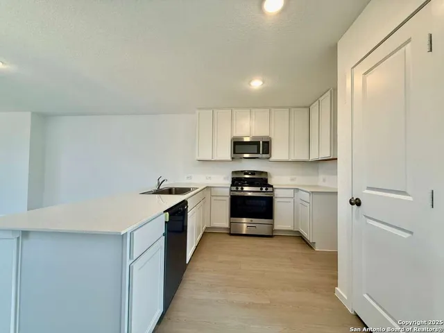 a large white kitchen with wooden floor