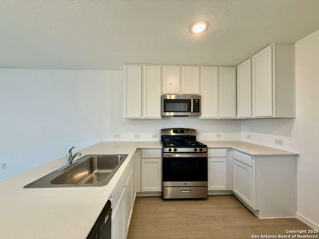 10319 Munoz Manor San Antonio, TX 78214 - Photo 6 of 13 a kitchen with sink a microwave and cabinets