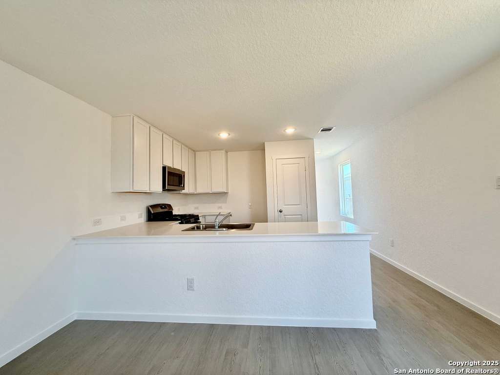 10319 Munoz Manor San Antonio, TX 78214 - Photo 7 of 13 a large white kitchen with wooden floor