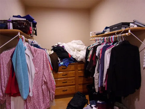 a view of walk in closet with clothes and shoes
