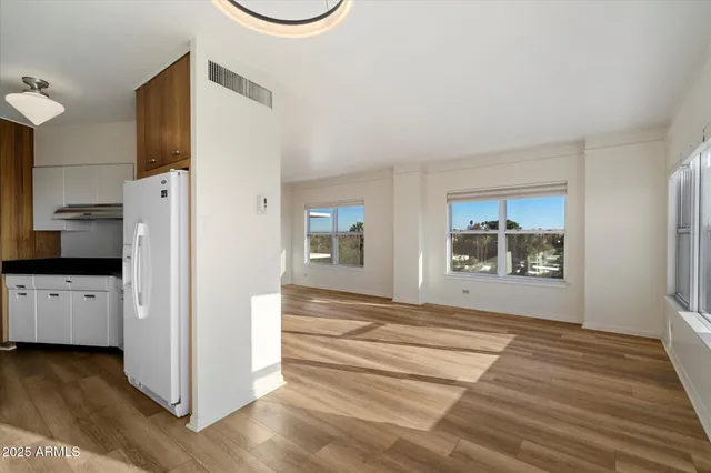 a view of a kitchen with a refrigerator a stove top oven a ceiling fan and wooden floor