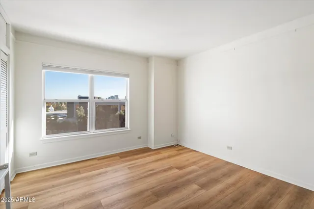 a view of empty room with wooden floor and fan