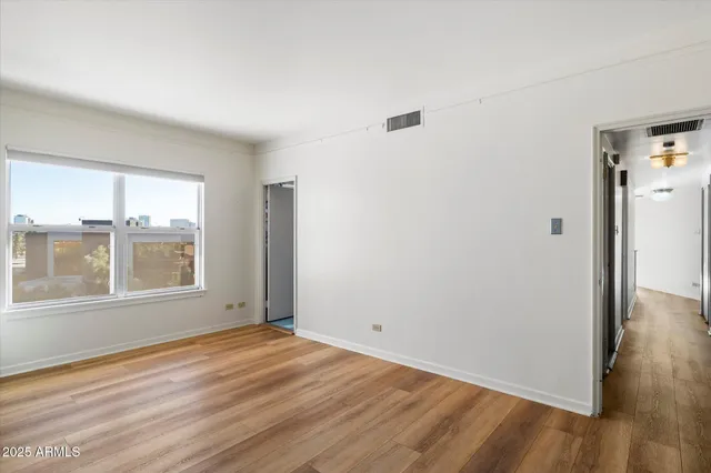 an empty room with wooden floor and windows
