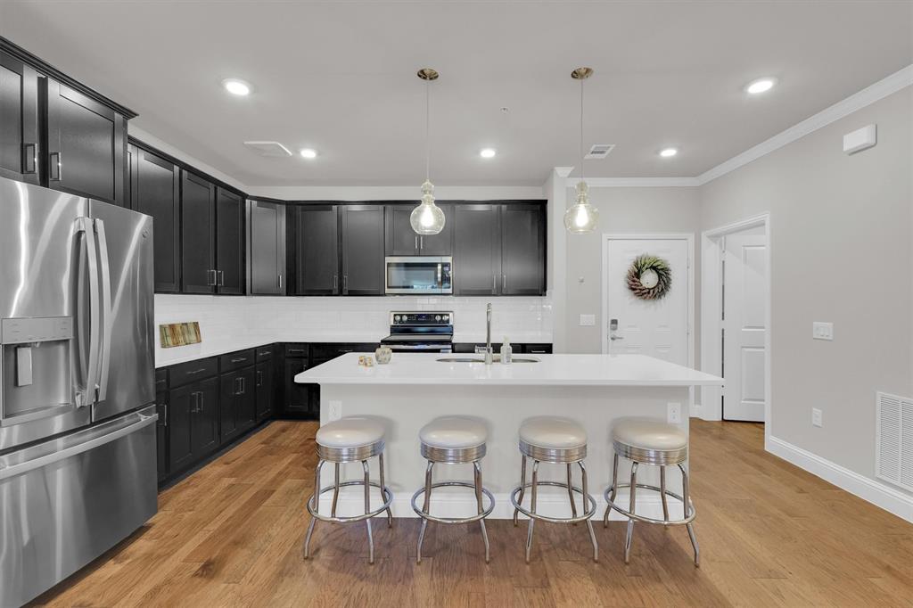 651 Watters Road, Unit 2105 Allen, TX 75013 - Photo 5 of 32 a kitchen with granite countertop a refrigerator a stove a sink a dining table and chairs