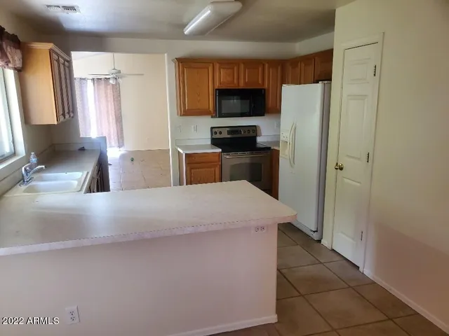 a kitchen with kitchen island a counter top space a sink a refrigerator and a stove