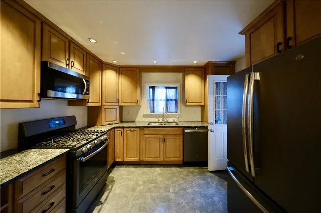 a kitchen with stainless steel appliances granite countertop a stove a sink and a refrigerator