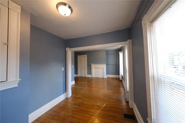 a view of a hallway with wooden floor and a bathroom